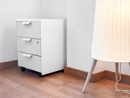 Minimalist white cabinet and modern lamp in bright corner of wooden floored roomの写真素材