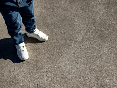 Young child wearing white sneakers on concrete surfaceの写真素材