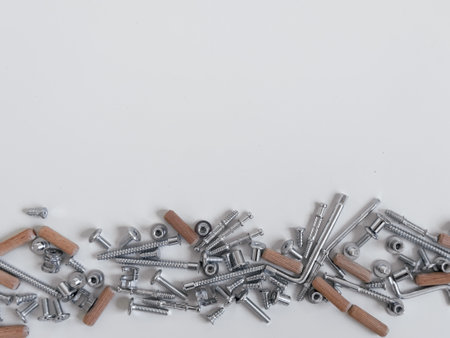 Assorted metal screws nuts bolts and wooden dowels on white surfaceの写真素材