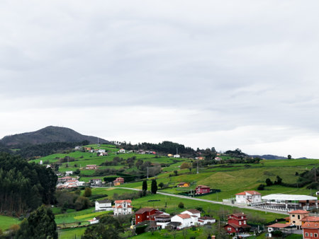 Scenic green hills and village landscape under cloudy skyの写真素材