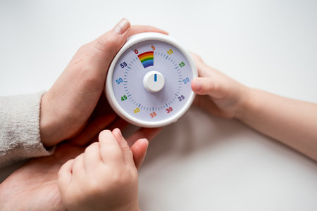 Adult and child hands holding colorful timer on white backgroundの写真素材