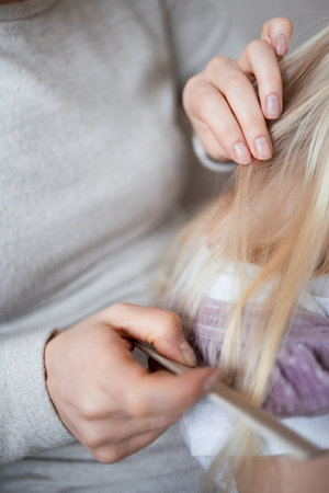 Adult caucasian female checking child blonde hair for lice with combの写真素材