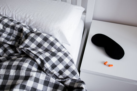 Cozy bedroom scene with black and white plaid blanket and sleep accessories on nightstand