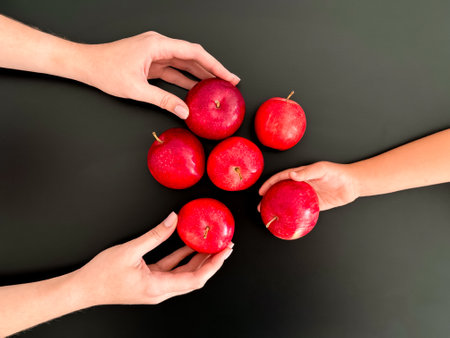 Hands holding red apples on black backgroundの写真素材