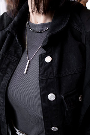 Stylish female in black denim jacket and silver necklace close upの写真素材