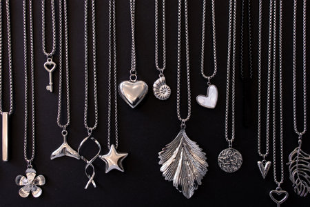 Various silver necklaces and pendants on black backgroundの写真素材