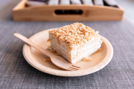 Delicious coconut cream cake slice on eco friendly plate with wooden forkの写真素材