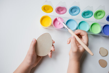 Child painting Easter egg with pastel colors on white backgroundの写真素材
