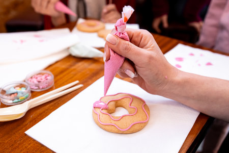 Decorating donuts with pink icing. Creative cookie design workshopの写真素材