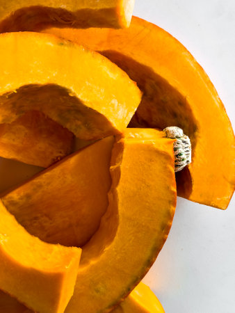 Close up of freshly sliced orange pumpkin with rind on white backgroundの写真素材
