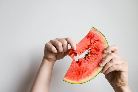 Hands holding juicy watermelon slice against white backgroundの写真素材