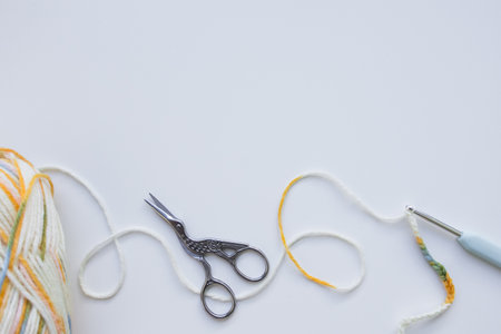 Yarn and crochet hook on white background with vintage scissors