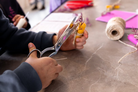 Young caucasian child crafting with scissors and yarn on a table