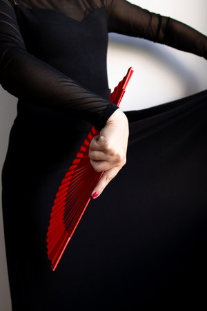 Female performer with red fan and black dress in motionの写真素材