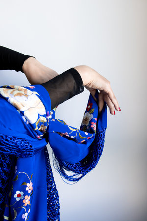 Elegant female hands in blue floral shawl with graceful gestureの写真素材