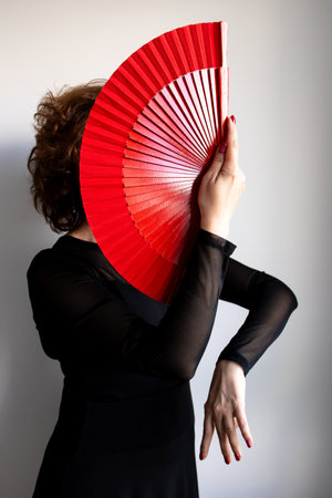 Female dancer with red fan in elegant black attireの写真素材
