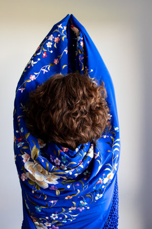 Back view of young caucasian female wrapped in blue floral scarf with curly hairの写真素材