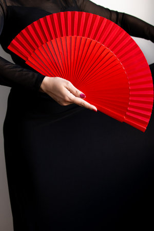 Female hand holding red fan against black background for flamenco dance conceptの写真素材