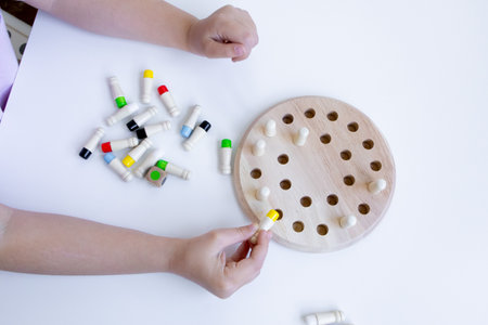 Child playing educational board game with wooden pegs and colored caps