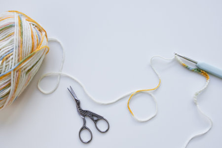 Colorful yarn ball with crochet hook and scissors on white backgroundの写真素材