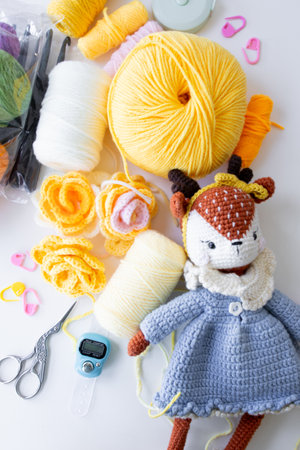 Crochet supplies and yarn with handmade deer plush toy on crafting tableの写真素材