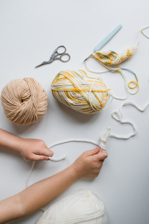 Child crafting with yarn and tools on white surface