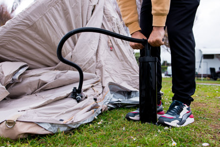 Man inflating tent with hand pump at campsiteの写真素材