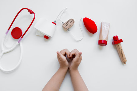 Child hands with toy medical tools on white background