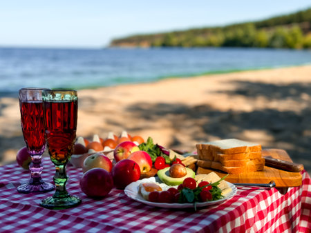 Summer beach picnic with fresh fruits, vegetables, and refreshing drinks by the seaの写真素材