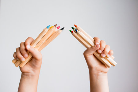 Child hands holding colorful pencils against white backgroundの写真素材