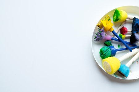 Colorful sponge painting tools on white plate for creative art projects