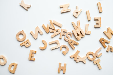 Scattered wooden alphabet letters on white background for learning and playの写真素材