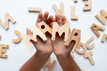 Child hands holding wooden letters spelling mama on white backgroundの写真素材