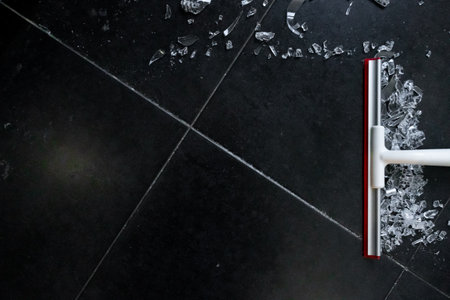 Broken glass cleanup on black tile floorの写真素材