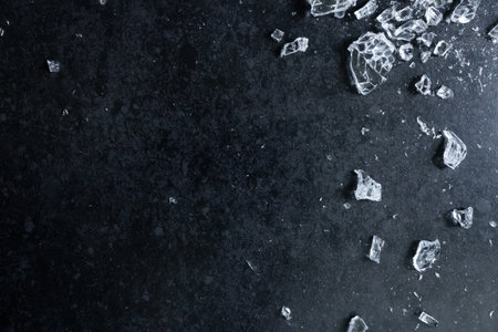 Shattered glass on dark surface with broken pieces and textured backgroundの写真素材