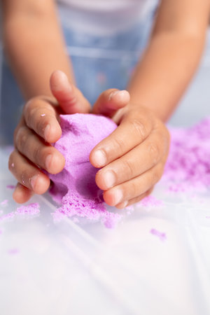 Child molding purple kinetic sand with handsの写真素材