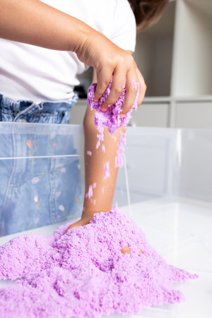 Child playing with purple kinetic sand in playroom settingの写真素材