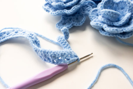 Blue crochet flowers and hook with yarn in creative craft settingの写真素材