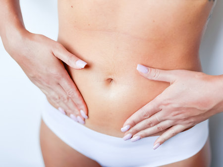 Close up of female caucasian young adult in white underwear touching flat stomachの写真素材