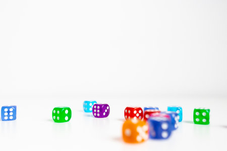 Colorful scattered dice on white background with focus on orange die in foregroundの写真素材