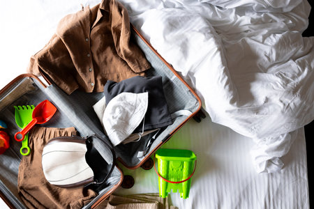 Packed suitcase with casual and beach clothing on unmade bedの写真素材