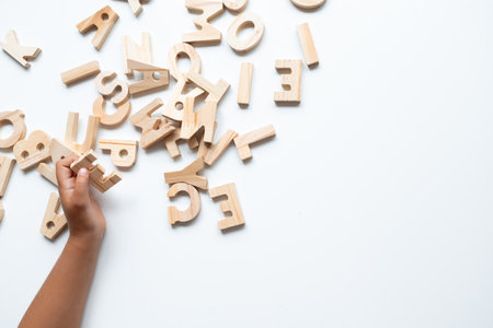 Caucasian child playing with wooden alphabet letters on white backgroundの写真素材