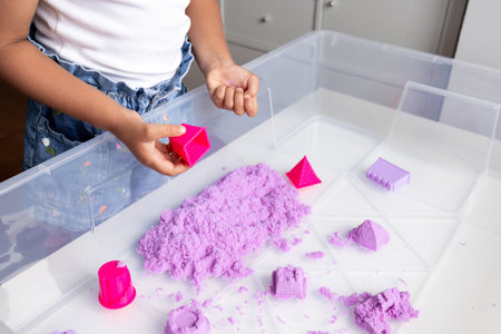 Child playing with purple kinetic sand and moldsの写真素材