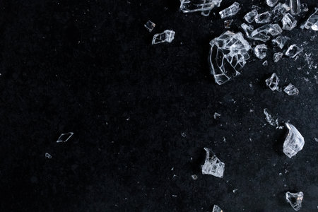 Shattered glass fragments on dark surface with high contrast and textureの写真素材