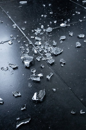 Broken glass shards on dark floor. Fragmented pieces and sharp edgesの写真素材