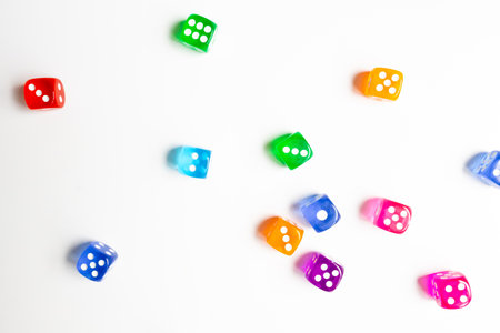 Colorful assorted dice scattered on white surfaceの写真素材