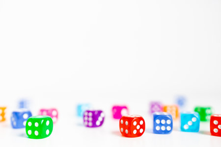 Colorful dice scattered on white surface for board games and entertainmentの写真素材