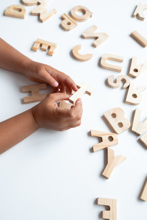 Child hands playing with wooden alphabet letters on white background