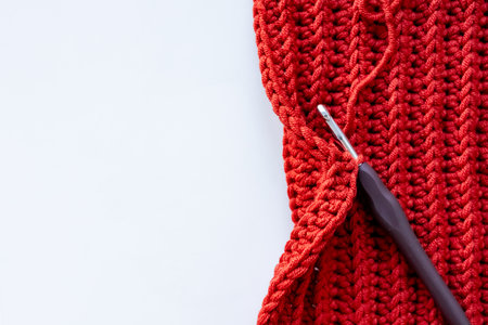 Red crochet project with hook on white background with copy space for textの写真素材