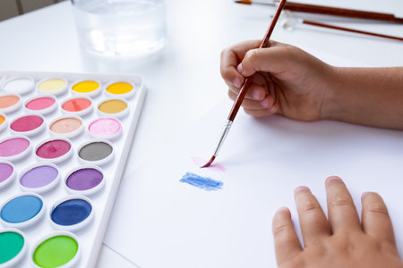 Child painting with watercolors on white paper. Creative art activityの写真素材
